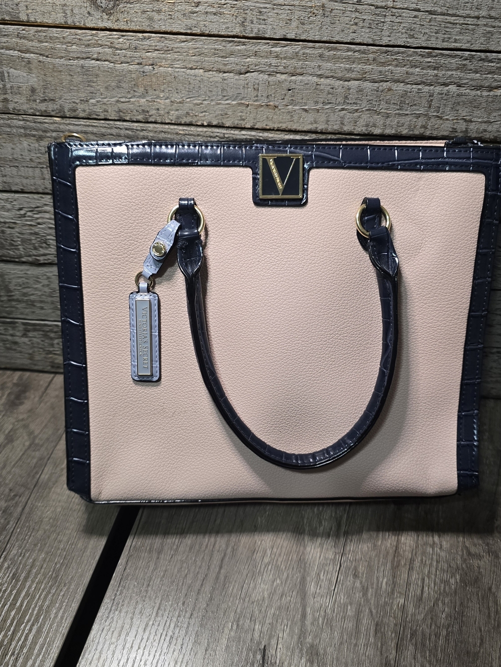 Victoria's Secret satchel handbag with a gold "V" logo and a matching blue tag.